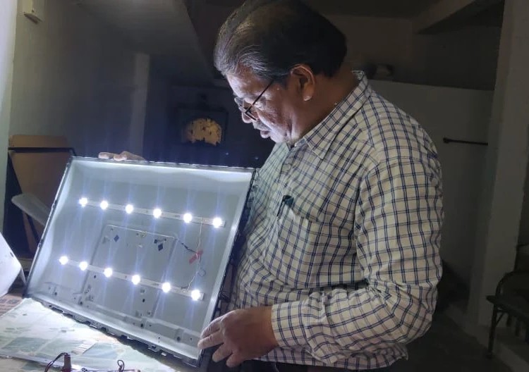 Rakesh Jain of M.R Electronics testing an LED backlight panel during a television repair in Indore